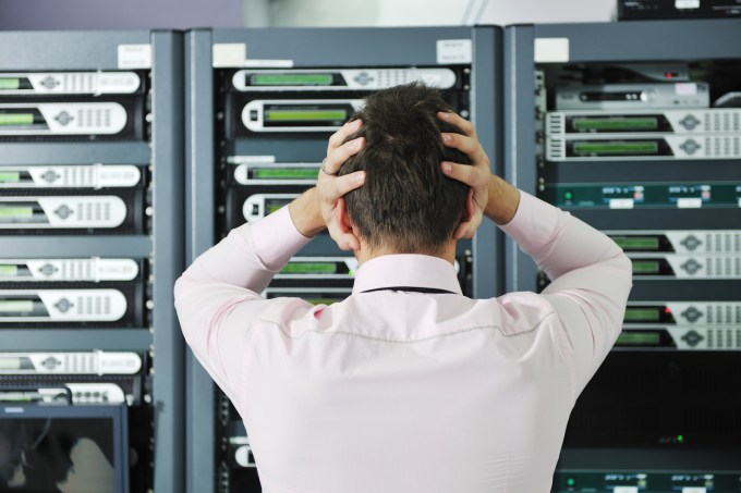Man holding head while he looks at server room disaster