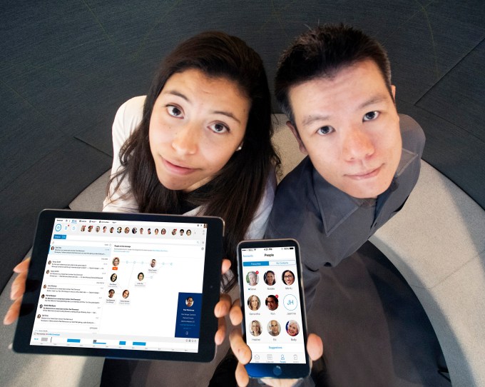 Two employees holding a tablet and smartphone with new IBM Verse email software.