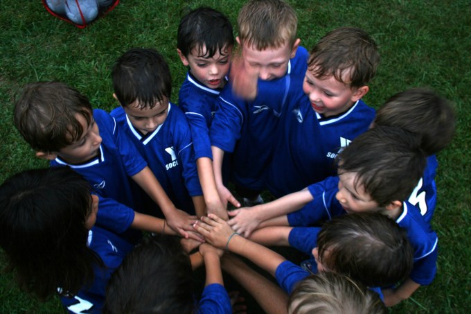 Group of young soccer players in blue uniforms in for an all for one moment before the game.