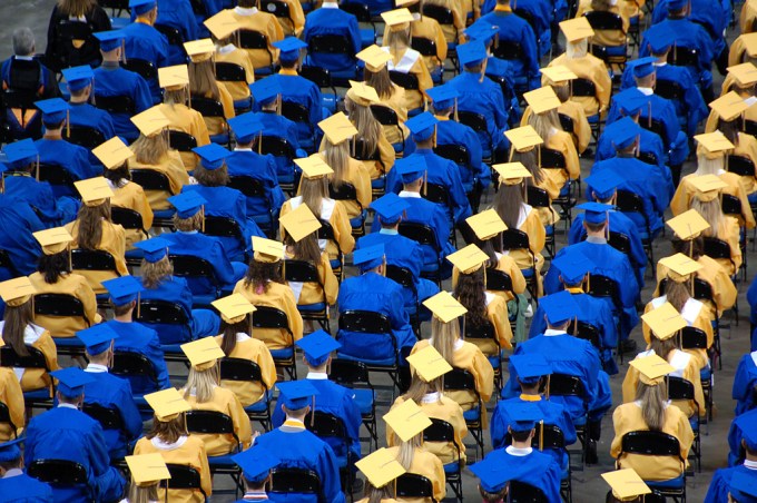 Sea blue and yellow caps and gowns on graduation day taken from air.