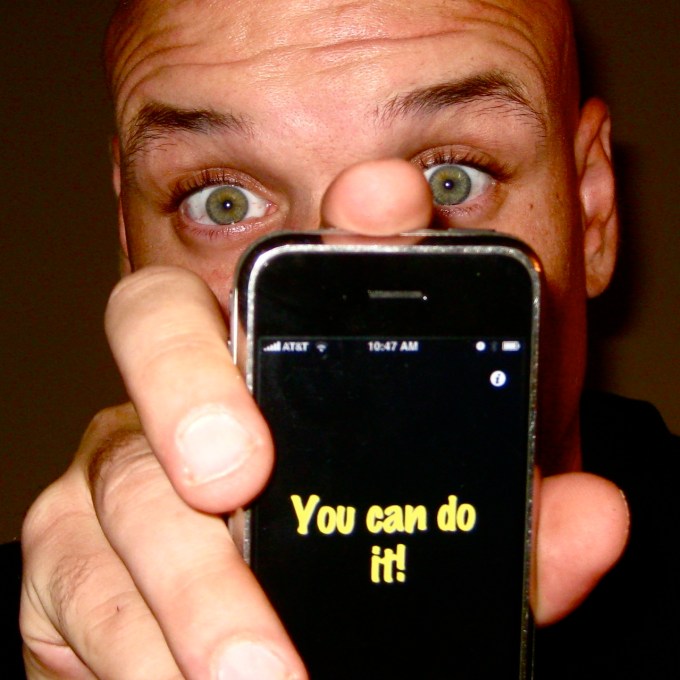Man holding old iPhone with You Can Do It! printed on back.