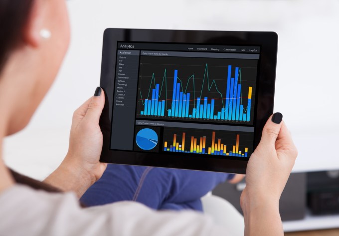 Cropped image of woman reading analytics/graphs on a tablet.