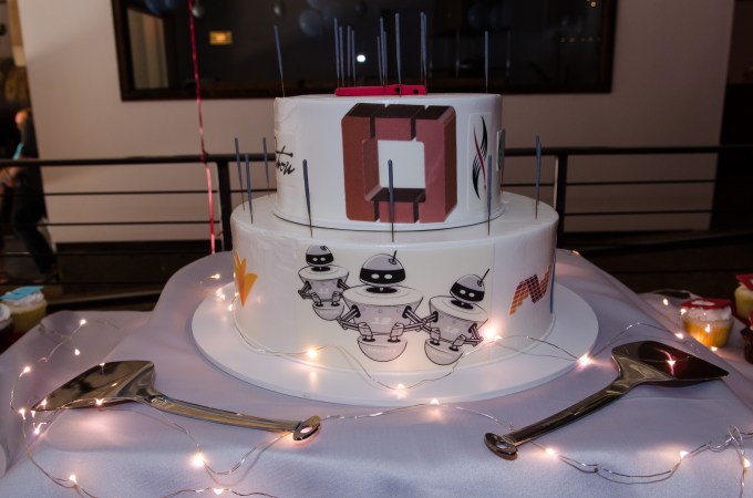Two-layer cake with OpenStack red O on one layer and three robots on the other.