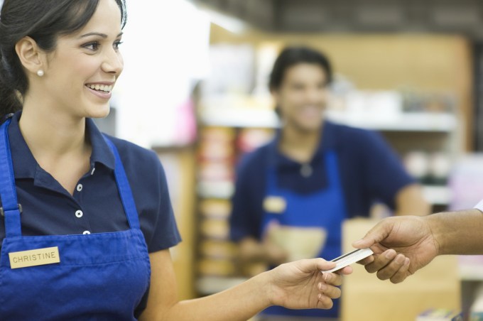 Female retail employee taking credit card.