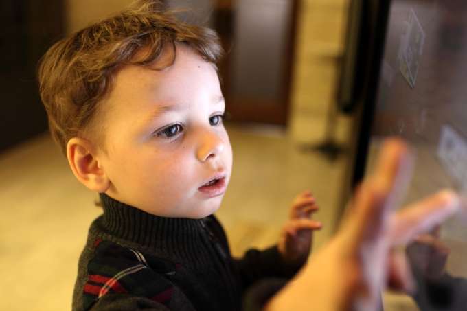 Little boy touching a computer screen.