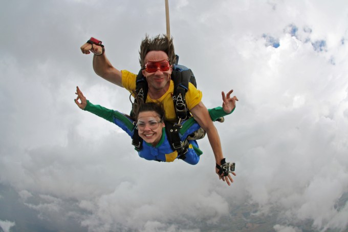 Two people parachuting together in the clouds.