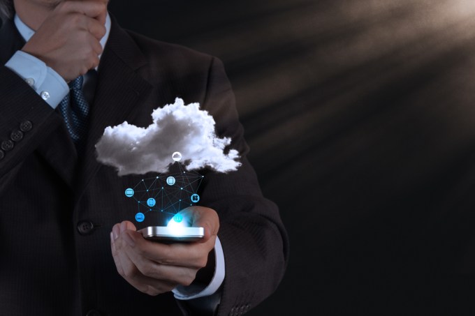 Business man holding smart phone connected via cloud.