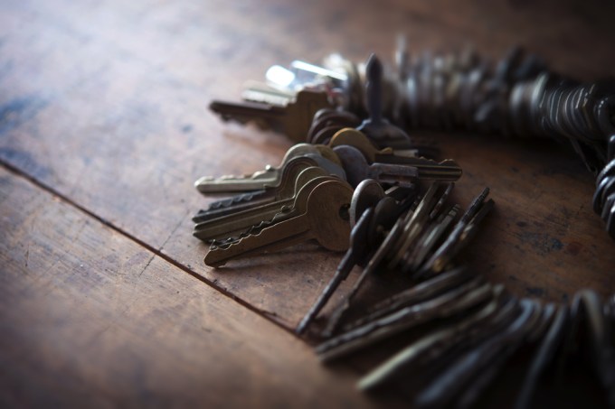 Set of keys on an old ring sitting on a warn wooden table.
