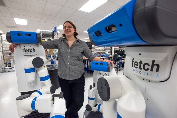 Melonee Wise, chief executive officer of Fetch Robotics Inc., stands for a photograph with the Fetch Robot at the company's headquarters in San Jose, California, U.S., on Tuesday, July 14, 2015. The Fetch Robotics system is comprised of a mobile base, called Freight and an advanced mobile manipulator called Fetch. Both robots use a charging dock for autonomous continuous operations, allowing the robots to charge when needed and then continue on with their tasks. Photographer: David Paul Morris/Bloomberg via Getty Images