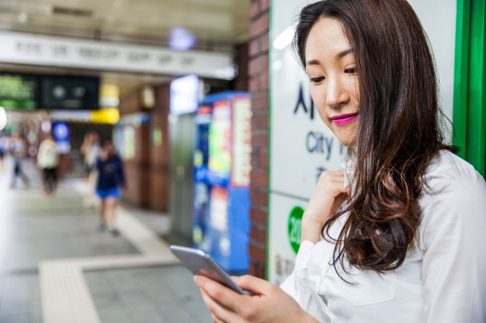 Smiling young business woman in subway station, South Korea. (Leonardo Patrizi/Getty Images)