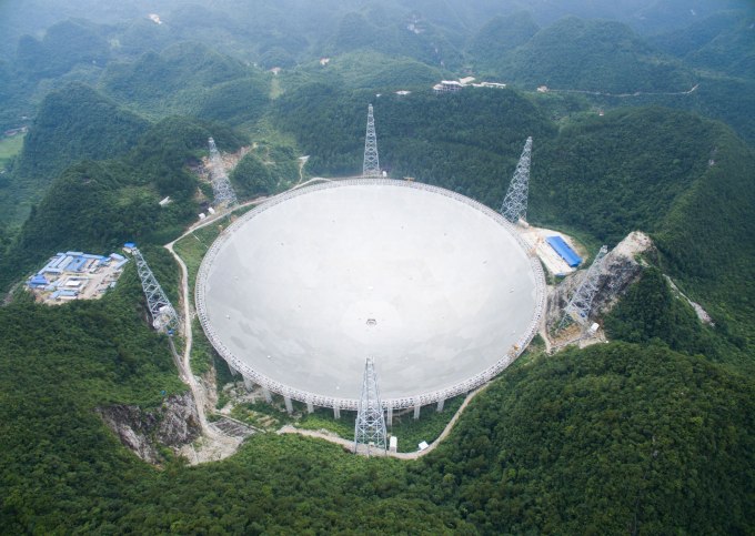 UNSPECIFIED, CHINA - JULY 03:  Workers lift the last panel to install into the center of a Five-hundred-meter Aperture Spherical Telescope (FAST) on July 3, 2016, China. The dish-like telescope, as large as 30 football fields, costing 1.2 billion yuan (about 180 million USD), will be used for reasearch and further adjustment according to China Daily.  (Photo by VCG/VCG via Getty Images)