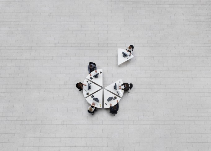 business in birds view, office seen from above with emploees sitting at their work stations in a formation shaped like a circle, one drawn away from her colleages