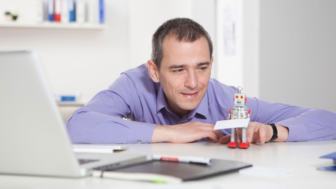 Man in office playing with toy robot holding card