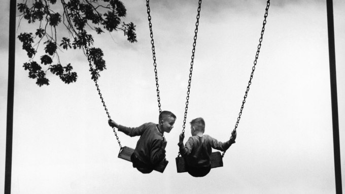 Two boys (6-8) on swings, rear view (B&W)