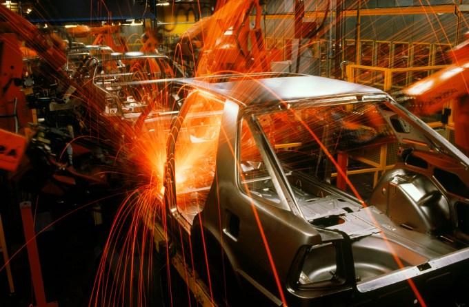 Sparks flying from spot welding robotics at automobile factory.