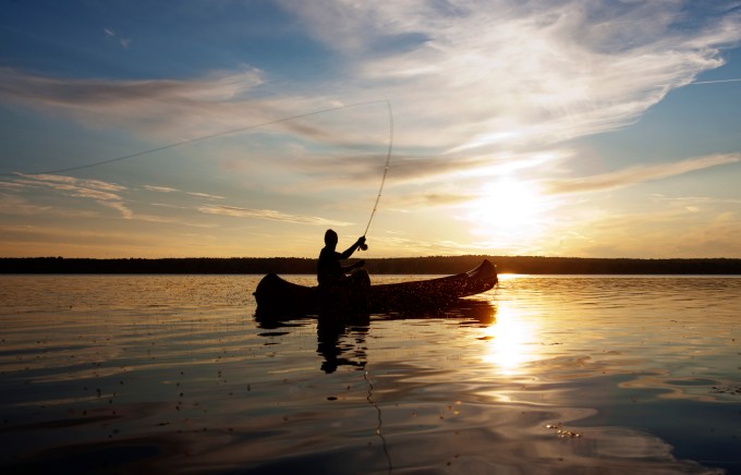 man fishing from canoe