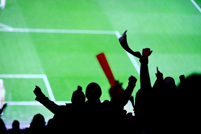 Sport fans cheering in football stadium.