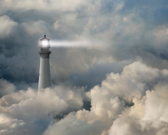 Lighthouse shining beam into thick clouds