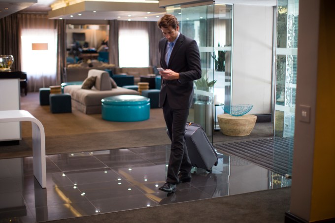 Businessman looking at smart phone while arriving at a hotel