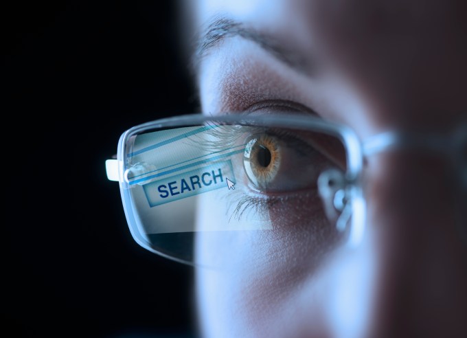 Woman with reflection of search button in her glasses.