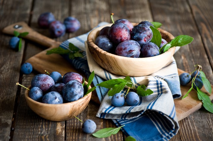 Plums in wooden bowl with napkin.