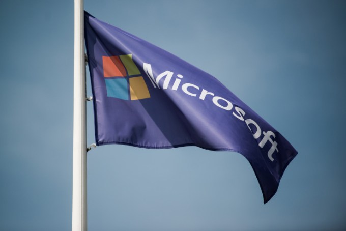A Microsoft logo sits on a flag flying in the grounds of the Nokia Oyj mobile handset factory, operated by Microsoft Corp., in Komarom, Hungary, on Monday, July 21, 2014. Microsoft said it will eliminate as many as 18,000 jobs, the largest round of cuts in its history, as Chief Executive Officer Satya Nadella integrates Nokia Oyj's handset unit and slims down the software maker. Photographer: Akos Stiller/Bloomberg via Getty Images