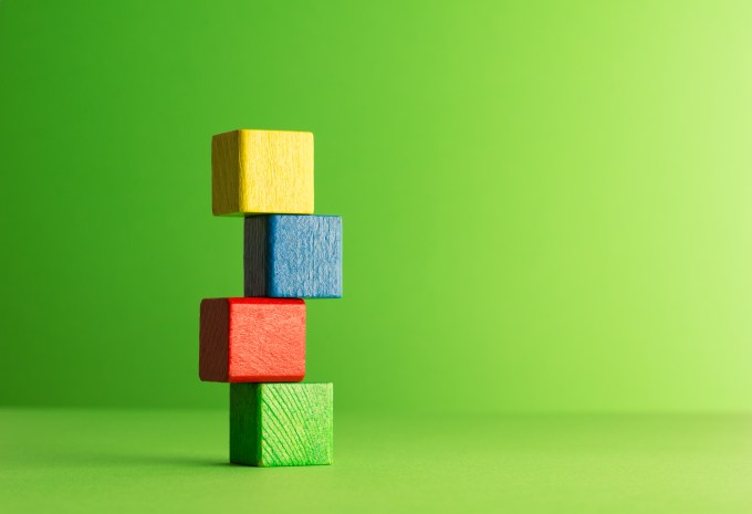Colorful wooden blocks stacked over green background