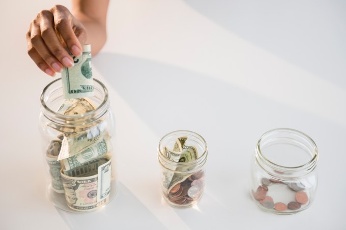 USA, New Jersey, Jersey City, Close up of woman's hand putting money into jar