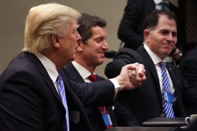 WASHINGTON, DC - JANUARY 23:  U.S. President Donald Trump (L) reaches across Alex Gorsky of Johnson & Johnson to shake hands with Michael Dell of Dell Technologies after saying his administration wants to reduce regulations on new investment during a meeting with business leaders and administraiton staff in the Roosevelt Room at the White House January 23, 2017 in Washington, DC. Business leaders also included Elon Musk of SpaceX, Mark Sutton of International Paper, Andrew Liveris of Dow Chemical, Marillyn Hewson of Lockheed Martin and others.  (Photo by Chip Somodevilla/Getty Images)