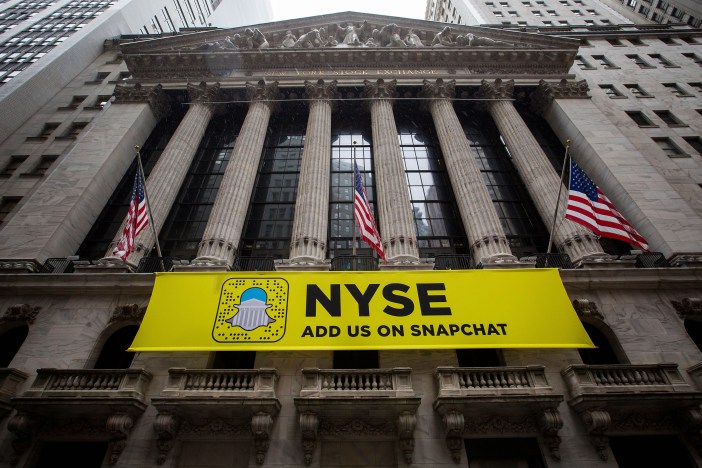 American flags fly above a Snapchat sign displayed outside of the New York Stock Exchange (NYSE) stands in New York, U.S., on Friday, Oct. 21, 2016. U.S. stocks trimmed losses as deal activity boosted consumer stocks and Microsoft Corp. rose toward a record, offsetting losses spurred by concerns a stronger dollar will damp corporate earnings. Photographer: Michael Nagle/Bloomberg via Getty Images
