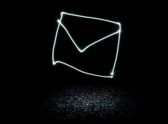 an envelope or letter made from light trails hovering above illuminated spot on beach
