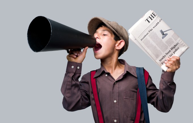 Newsboy wearing flat hat holding newspaper and shouting to sell.Megaphone in right hand, and newspapers in left hand.Model is wearing red suspenders.The image was shot with Hasselblad H4D